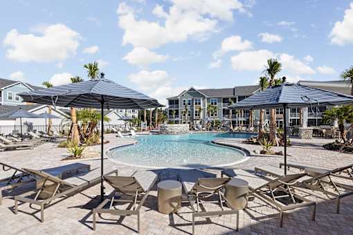 A pool surrounded by chairs and umbrellas.