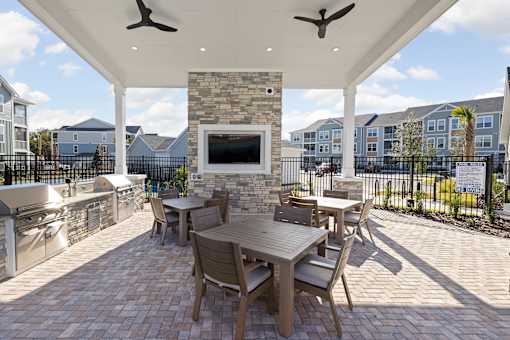 A patio with a table and chairs and a stone fireplace.