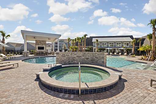 A large outdoor swimming pool with a hot tub in the middle.