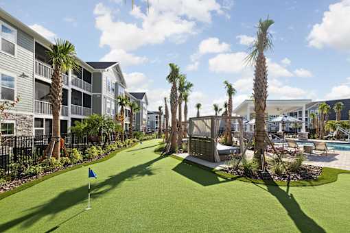 A miniature golf course is surrounded by palm trees and a pool.
