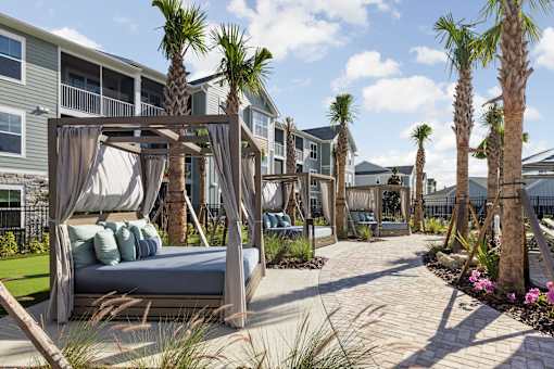 A canopy bed is in the middle of a walkway with palm trees on either side.