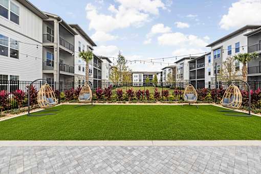 A well-maintained lawn area with swing chairs and apartment buildings in the background. at Terrassa Luxury Apartments, Florida, 32084