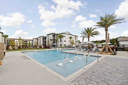 A large swimming pool surrounded by palm trees and lounge chairs. at Terrassa Luxury Apartments, St. Augustine