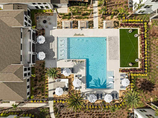 An aerial view of a pool surrounded by palm trees and lounge chairs. at Terrassa Luxury Apartments, St. Augustine, Florida
