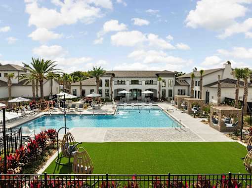A large swimming pool surrounded by a grassy area and palm trees. at Terrassa Luxury Apartments, St. Augustine