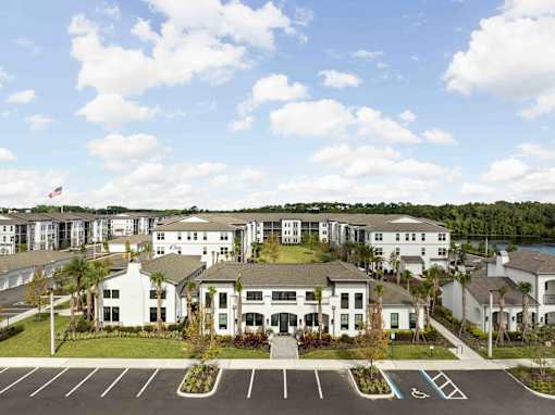 A large white building with a flag on top is surrounded by a parking lot. at Terrassa Luxury Apartments, St. Augustine, 32084