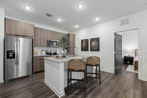 A kitchen with a refrigerator, microwave, and a counter with two chairs. at Terrassa Luxury Apartments, St. Augustine, FL, 32084
