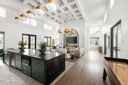 A modern kitchen with dark green cabinets and a long wooden island.