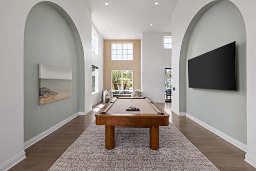 A billiard table is in the middle of a room with arched walls.