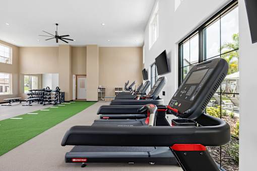 A gym with treadmills and a fan.