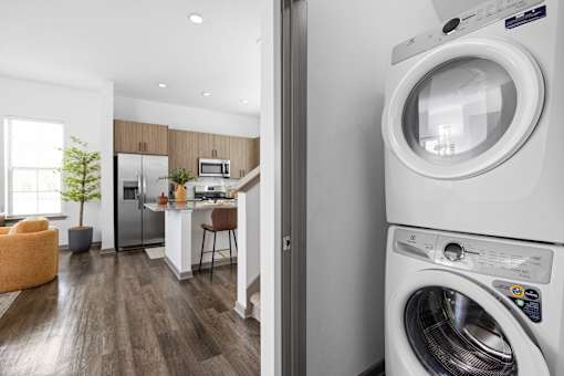 A modern laundry room with a washing machine and a view into a kitchen.