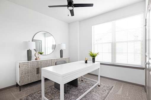 A room with a white table and a round mirror on the wall.
