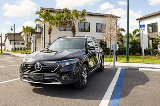 A black Mercedes-Benz EQC is parked in a parking spot with a charging station.
