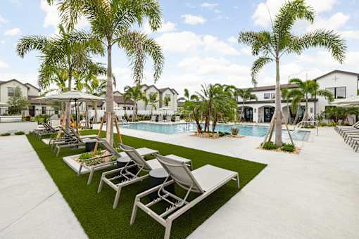 A pool surrounded by palm trees and lounge chairs.