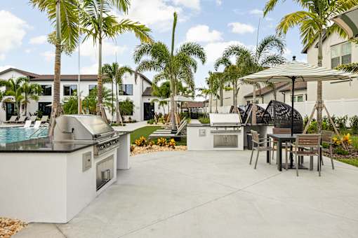 A patio with a grill and chairs under a canopy.