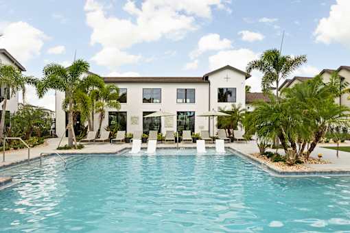 A swimming pool in front of a white building with a cross on it.