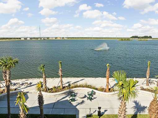 A view of a lake with palm trees and a jet ski in the water. at Junction Apartments in Rockledge, FL
