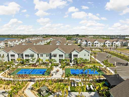A large residential complex with a swimming pool and tennis courts. at Junction Apartments in Rockledge, FL