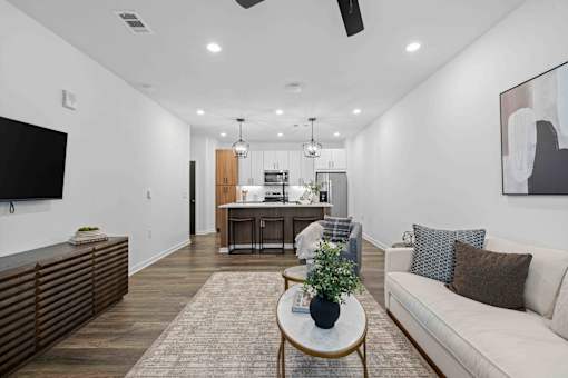A living room with a white couch, a coffee table, and a television. at Junction Apartments in Rockledge, FL