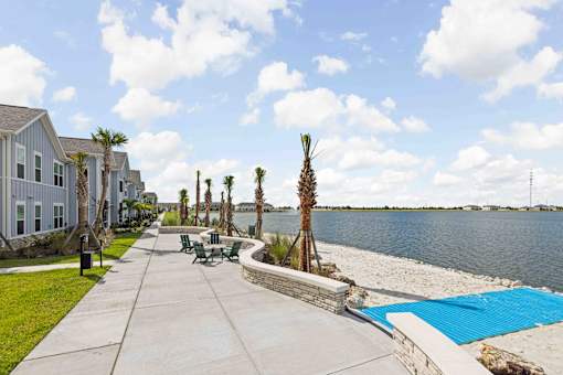 A view of a walkway with a pool and palm trees. at Junction Apartments in Rockledge, FL