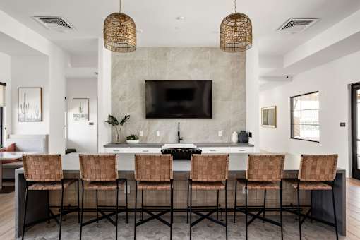 A modern kitchen with a bar area and chairs.