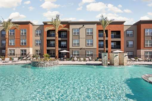 A large swimming pool in front of a multi-story apartment building.