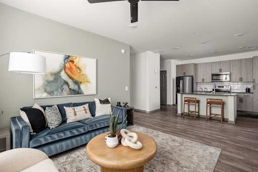 A living room with a blue couch and a painting on the wall.