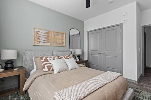A bedroom with a bed, nightstand, and a painting on the wall.