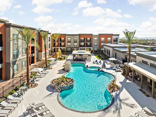 A large swimming pool surrounded by lounge chairs and palm trees.