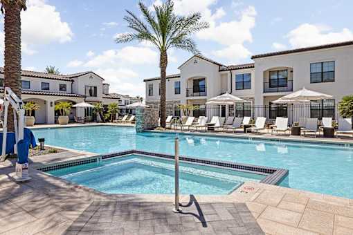 A pool surrounded by lounge chairs and umbrellas with a building in the background.at Stella, San Tan Valley Arizona