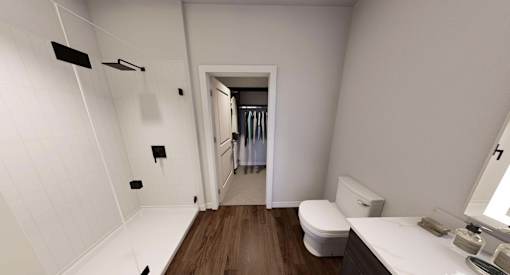 A white bathroom with a toilet, sink, and mirror at Stack at Wheat Ridge Apartments, Wheat Ridge