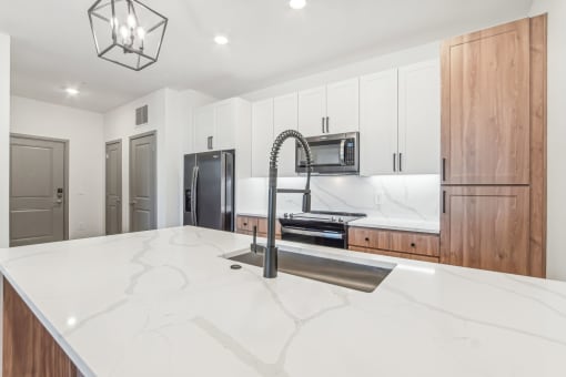 a large kitchen with white counter tops and a sink at The Maddox Luxury Apartment Homes, Buckeye Arizona  