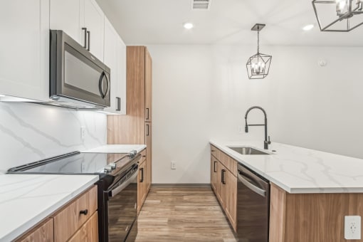 a renovated kitchen with marble counter tops and wooden cabinets at The Maddox Luxury Apartment Homes, Arizona  