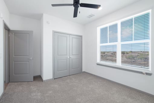 an empty room with a large window and a ceiling fan at The Maddox Luxury Apartment Homes, Buckeye, AZ 85326  