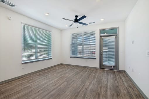 an empty living room with a ceiling fan and two windows at The Maddox Luxury Apartment Homes, Arizona  