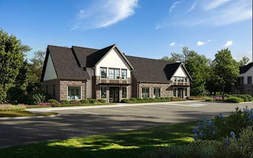 A large building with a black roof and white walls is surrounded by a grassy area and trees.