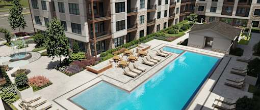 A large swimming pool surrounded by lounge chairs and trees.