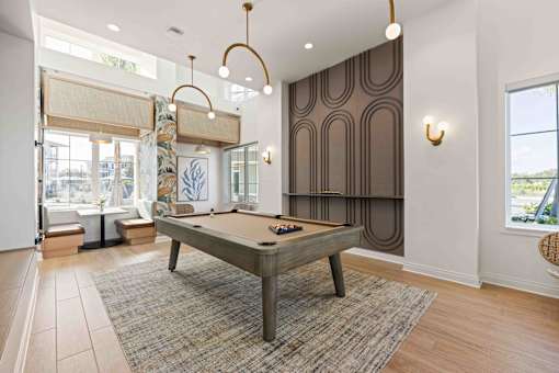A pool table is in the middle of a room with a brown carpet at Verity Luxury Apartments, Florida 32960