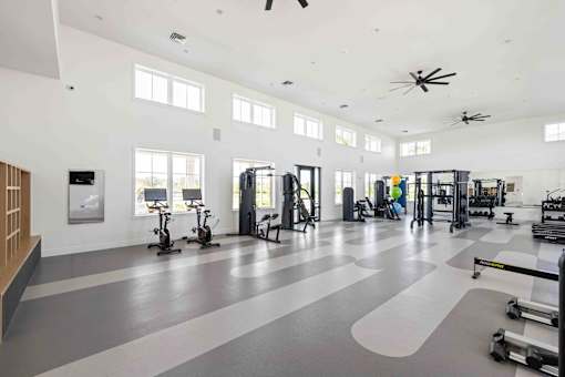A spacious gym with a variety of equipment and a large mirror on the wall at Verity Luxury Apartments, Florida