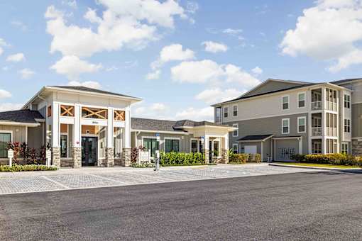 A large building with a covered entrance and a parking lot in front at Verity Luxury Apartments, Vero Beach, FL 32960