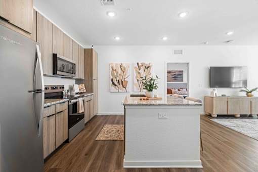 A modern kitchen with wooden cabinets and a large island at Verity Luxury Apartments, Vero Beach, FL 32960