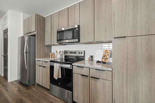 A modern kitchen with wooden cabinets and stainless steel appliances at Verity Luxury Apartments, Vero Beach