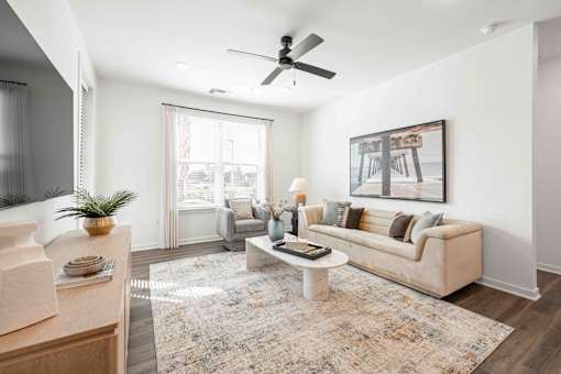 A living room with a beige couch, a rug, and a painting on the wall at Verity Luxury Apartments, Vero Beach, FL