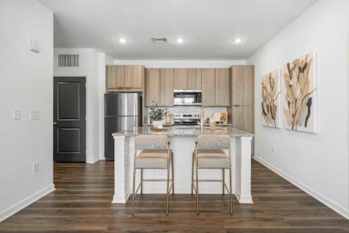 A kitchen with a refrigerator, oven, and a counter with two chairs at Verity Luxury Apartments, Florida 32960