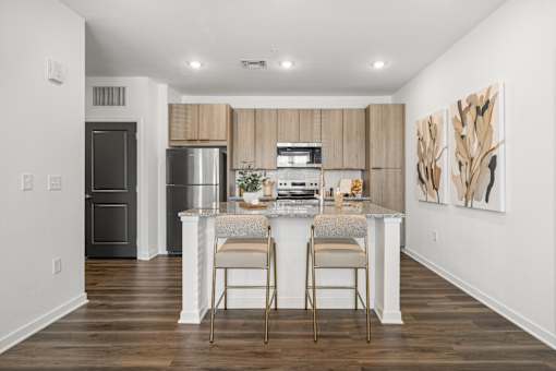 A kitchen with a white island and two chairs at Verity Luxury Apartments, Florida 32960