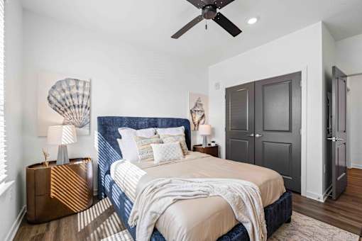A bedroom with a bed, a ceiling fan, and a wooden nightstand at Verity Luxury Apartments, Florida