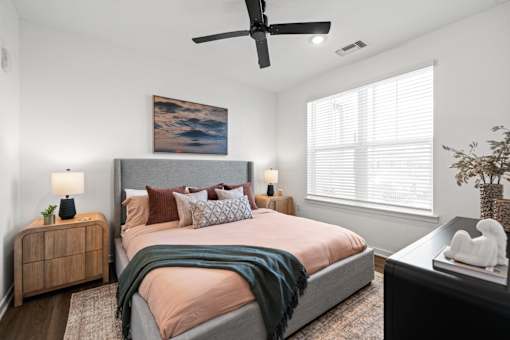 A bedroom with a bed, a ceiling fan, and a painting on the wall at Verity Luxury Apartments, Vero Beach, Florida