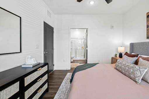 A bedroom with a bed, nightstand, and a painting on the wall at Verity Luxury Apartments, Vero Beach, FL 32960