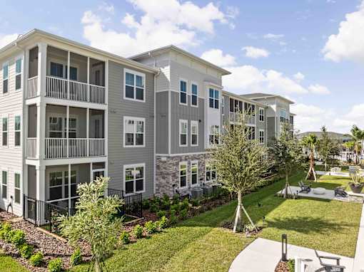 A large apartment complex with a well-maintained lawn and landscaping at Verity Luxury Apartments, Florida 32960