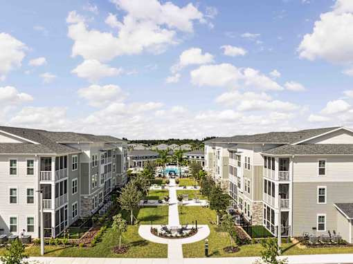 A view of a courtyard surrounded by apartment buildings at Verity Luxury Apartments, Vero Beach, FL